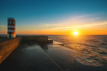 Beautiful sunset on the sea a stone pier. Atlantic coast in Portugal.