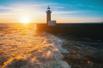 Beautiful sunset on the sea a stone pier and lighthouse. Atlantic coast in Portugal.