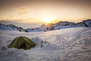 Mountaineering tent in the winter landscape surrounded by the mountain peaks at the sunset © Dimitrije Ostojic