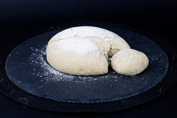 Homemade organic Dough for pizza or bread on black slate stone plate 