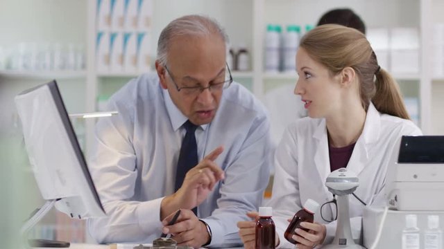  Workers in a chemist shop checking stock & discussing their work