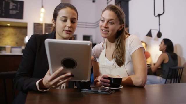  Sales rep with computer tablet negotiating a deal with cafe owner