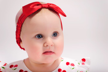 Little girl in white with a red dress with a bow on her head