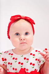 Little girl in white with a red dress with a bow on her head