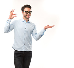 Young happy man showing presentation, pointing on placard over gray background