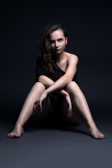 Fototapeta na wymiar Young beautiful girl poses sexually on a black background