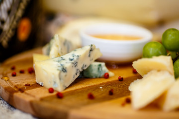 Different types of Italian cheeses (Parmesan, Gorgonzola, Roquefort) are on the Board. Macro.