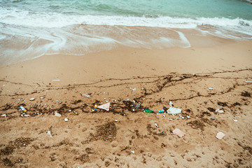 The sea shore in the garbage. Environmental pollution. Garbage on the sandy beach.
