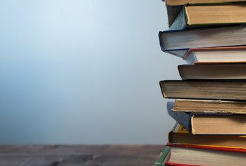  Books in a stack in right side on the wooden table. Wall at the background.