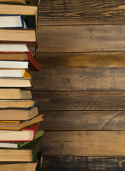 Books in a stack in left side with the grunge wooden table background.