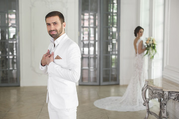 Chic wedding couple groom and bride posing in a white Studio. Happy couple laughing. White dress....