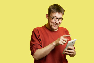 A smiling man in glasses uses a tablet.
