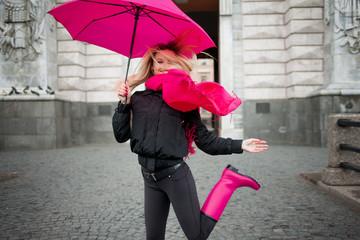 Beautiful young and happy blond woman with colorful umbrella on the street. The concept of...