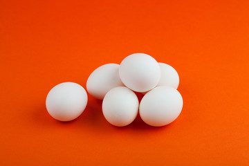 Chicken eggs on an orange background are stacked.