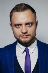 Portrait of serious fashionable handsome man in blue suit looking at camera