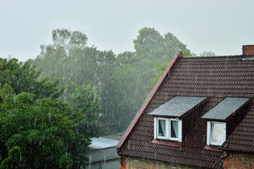 Fototapeta na wymiar Deszcz padający na dach z oknem.