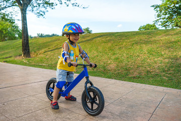 A cute little boy riding a balance bike in the park