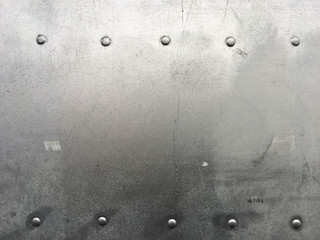 Riveted metal background, detail metal textured background from aircraft. Old grunge metal fragment of protective structure made of metal plates sheets assembled with button head rivets.