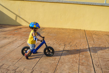 A cute little boy riding a balance bike in the park.