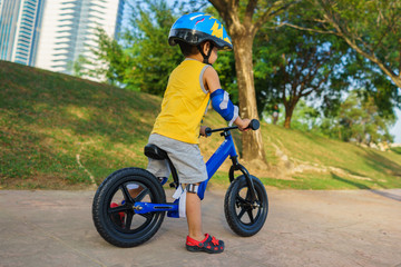 A cute little boy riding a balance bike in the park.