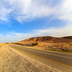 Fototapeta na wymiar Empty road in a mountains in desert at sunset