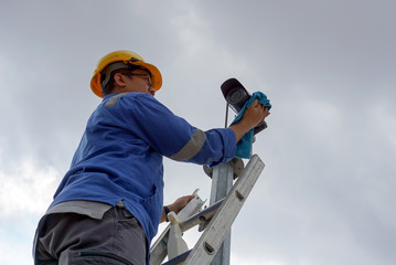 A male worker doing a maintenance work by cleaning and inspecting security camera.