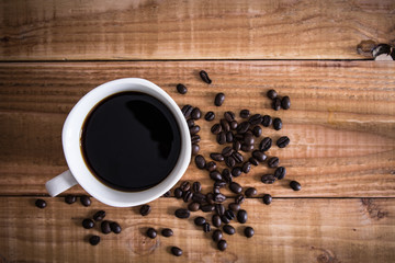 Coffee cup and coffee beans on wooden background. Top view.