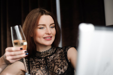 Woman in a restaurant relaxing with glass of champagne and tablet pc