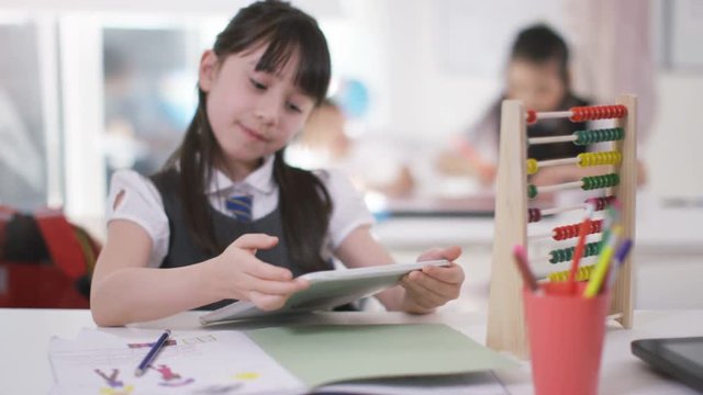  Young school children in class little girl using abacus & computer tablet