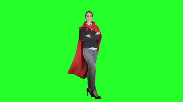 
triumphantly beautiful young woman business leader is dressed in red Cape on a green background