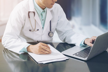 Doctor working on desk with laptop