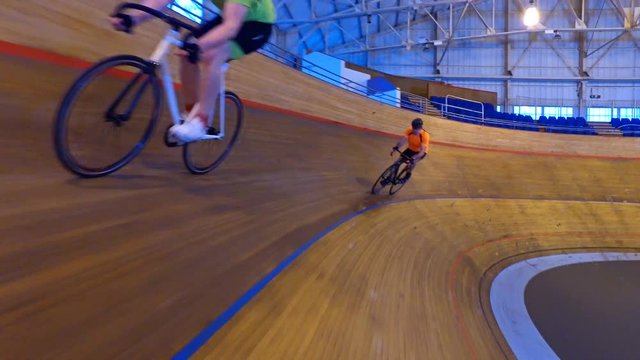  Action tracking shot of competitive cyclists racing on track in velodrome