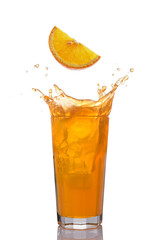 Fototapeta na wymiar Splash in glass of juice with falling slice of orange