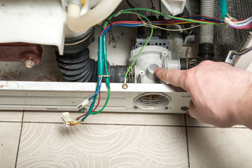 Repair old laundry washer. Pointing to a pump.