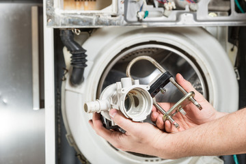 Repair old laundry washer. Old water pump and heater  are in the hands of men.