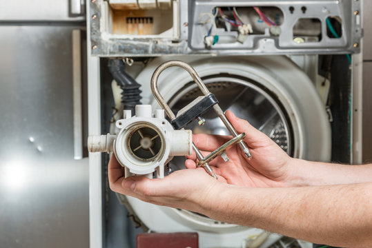 Repair old laundry washer. Old water pump and heater  are in the hands of men.