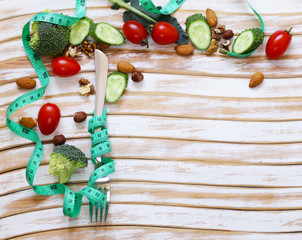 Diet concept - fork with measuring tape on a wooden table