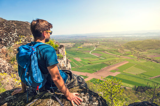 Hiker with backpacks relaxing on top of a mountain and enjoying the view of valley