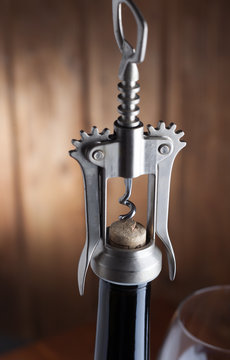 Corkscrew and a glass of wine on an old wooden table