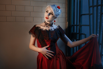 Woman with a vampire fangs, in a red dress.