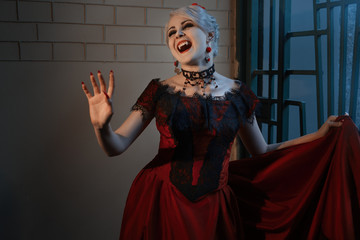 Woman in red dress with vampire grin, Victorian style.