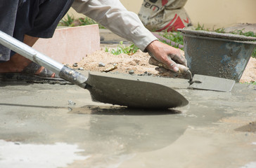 Hand of labour man using plastering and take the cement in to the bucket