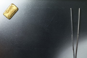 Forceps and gold bar put on stainless tray represent surgery and medical business concept.