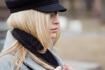 Young, hip and attractive blonde walking around the city, girl in a stylish hat and a gray coat