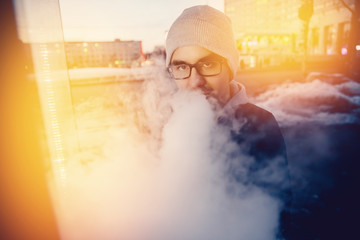 vaping man holding a mod device. cloud of vapor. Vape. high contrast and monochrome color tone.