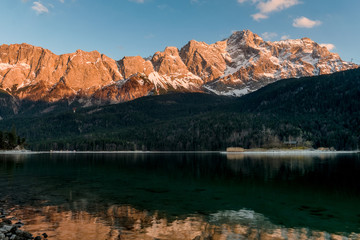 Fototapeta na wymiar Alpine sunset with beautiful lit mountains in the background and the Eibsee lake in the foreground