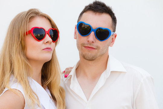 Man and woman wearing heart shape sunglasses