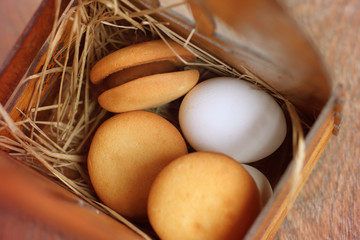 Bisquit cakes and fresh egg in a box of hay