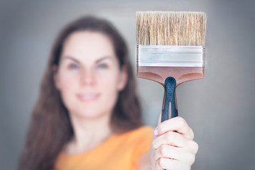 Smiling young woman holding a paint brush blurred