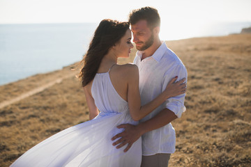 Beautiful young couple hugging in nature. People in white clothes.